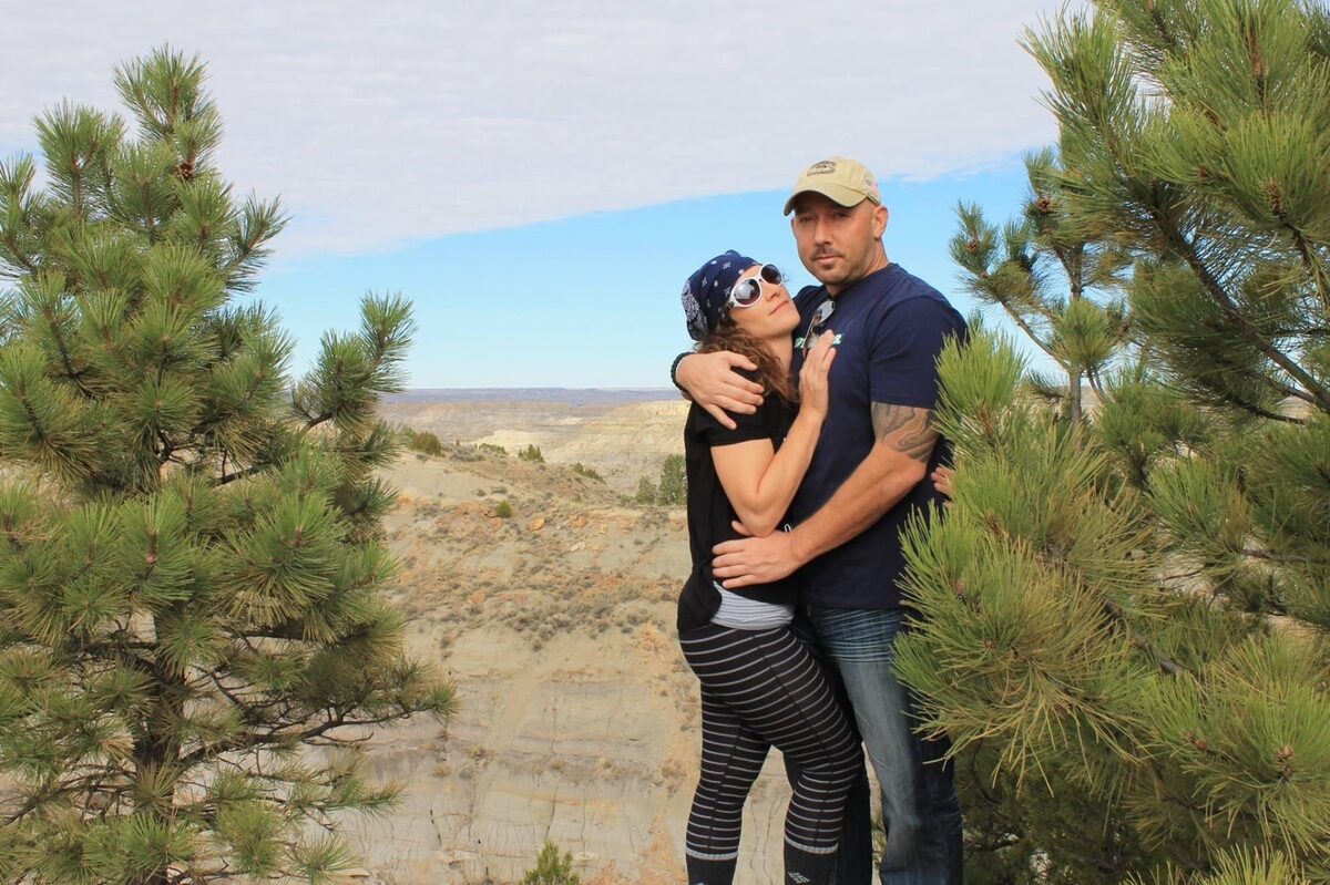 Shayne posing outdoors with a loved one against a Badlands rock-formation backdrop.